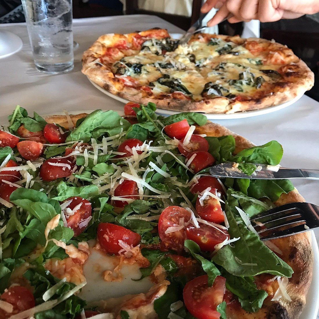 Brick-oven pizzas at Amancio's Pizza Pasta & Drinks in Jacó, including an arugula, tomato and parmesan pie