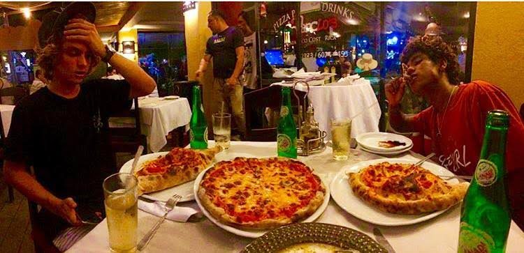 Evening table with pizzas and drinks outside Amancio's Pizza Pasta & Drinks in Jacó