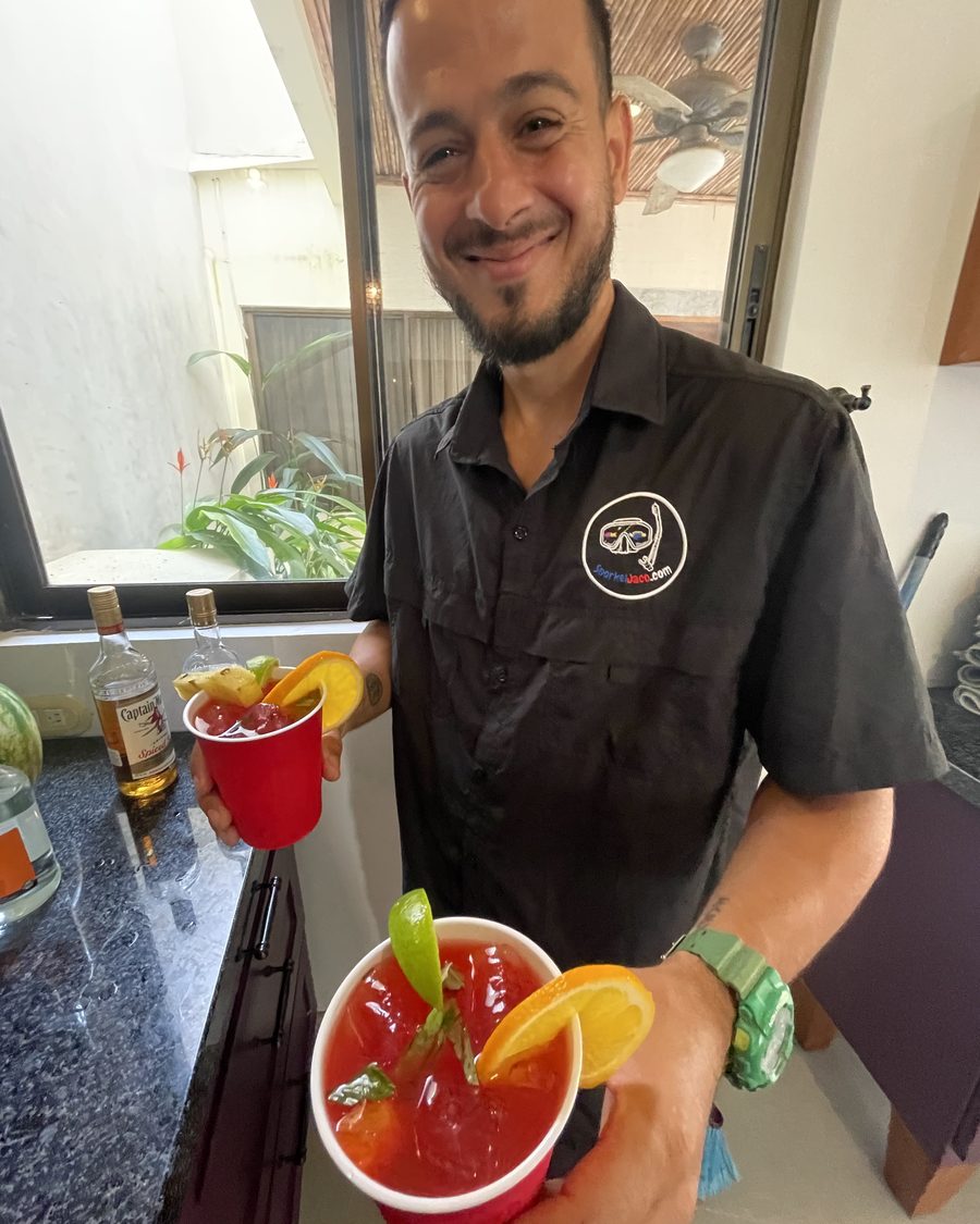 Chef Bill'ardee in his Jaco Beach Chef polo holding two fresh garnished cocktails