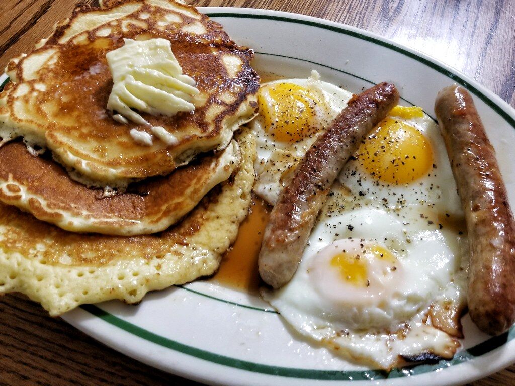 Fluffy pancakes with fried eggs and breakfast sausage from a private chef in Jaco Beach
