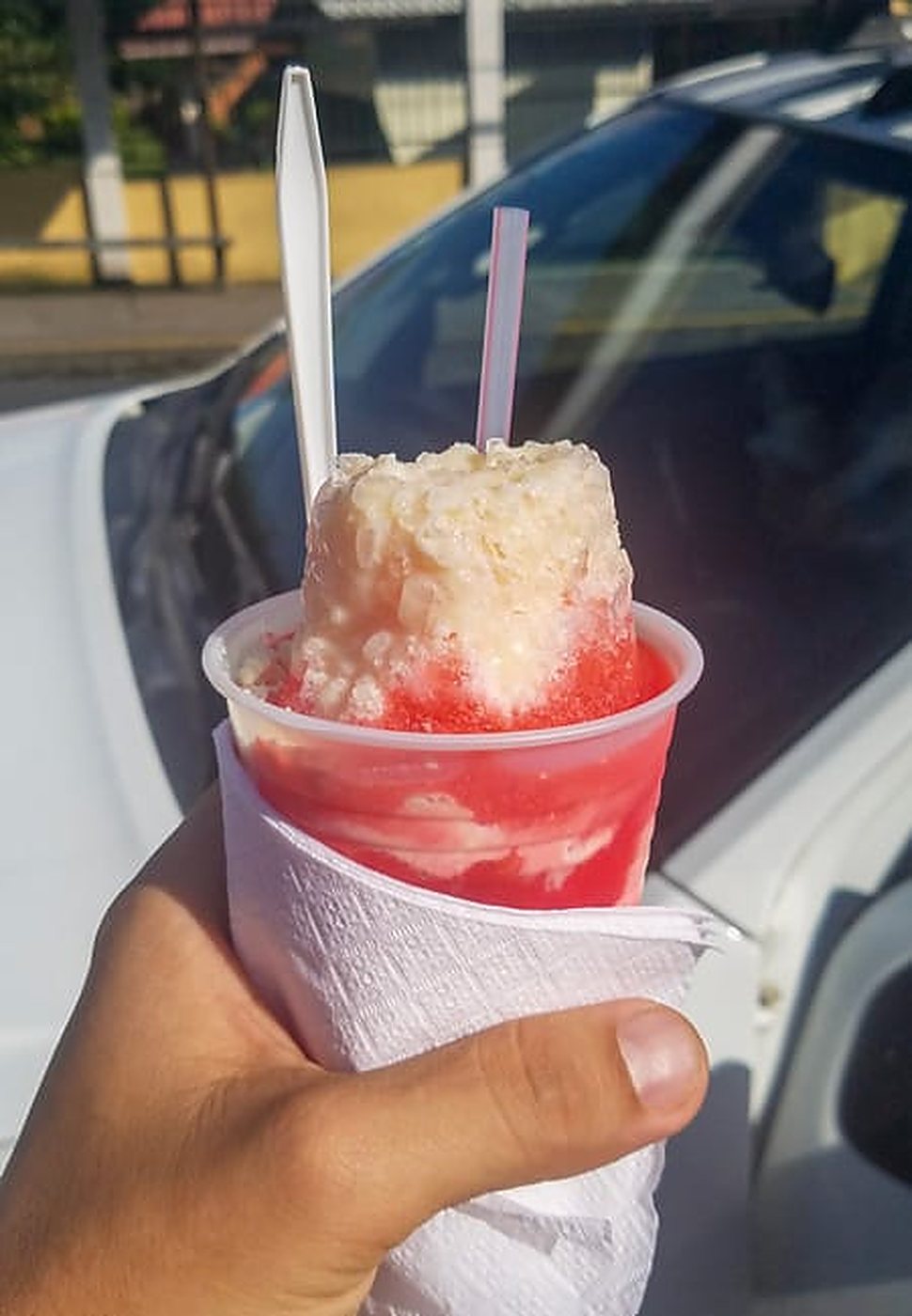 A Costa Rican granizado of red shaved ice topped with condensed milk, bought from a street cart