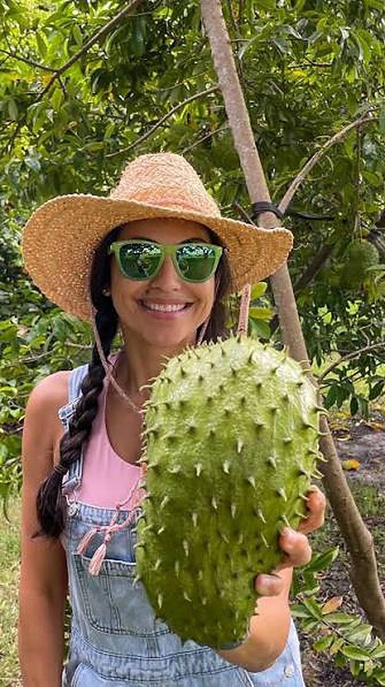 A woman holding a large guanabana (soursop) fruit fresh off the tree