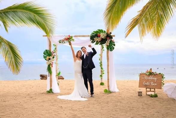 wedding planner Jaco Beach — couple celebrating at beach wedding arch, destination wedding Jacó Beach Costa Rica