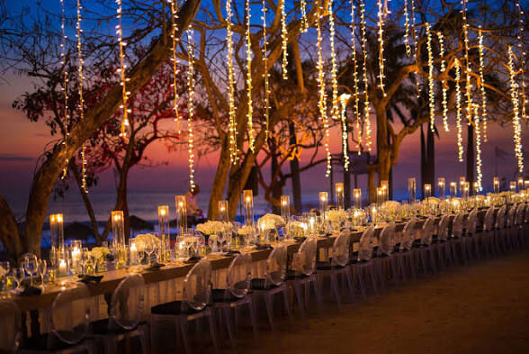 Private outdoor dinner reception with festive string lights over the table, set up for a bachelorette party in Jacó Beach overlooking the ocean