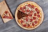 Little Caesars supreme pizza on a wood board in Jacó