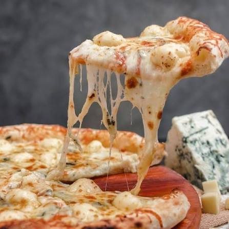 Four-cheese pizza with a gooey cheese-pull slice at Pizza Luciano's in Jacó