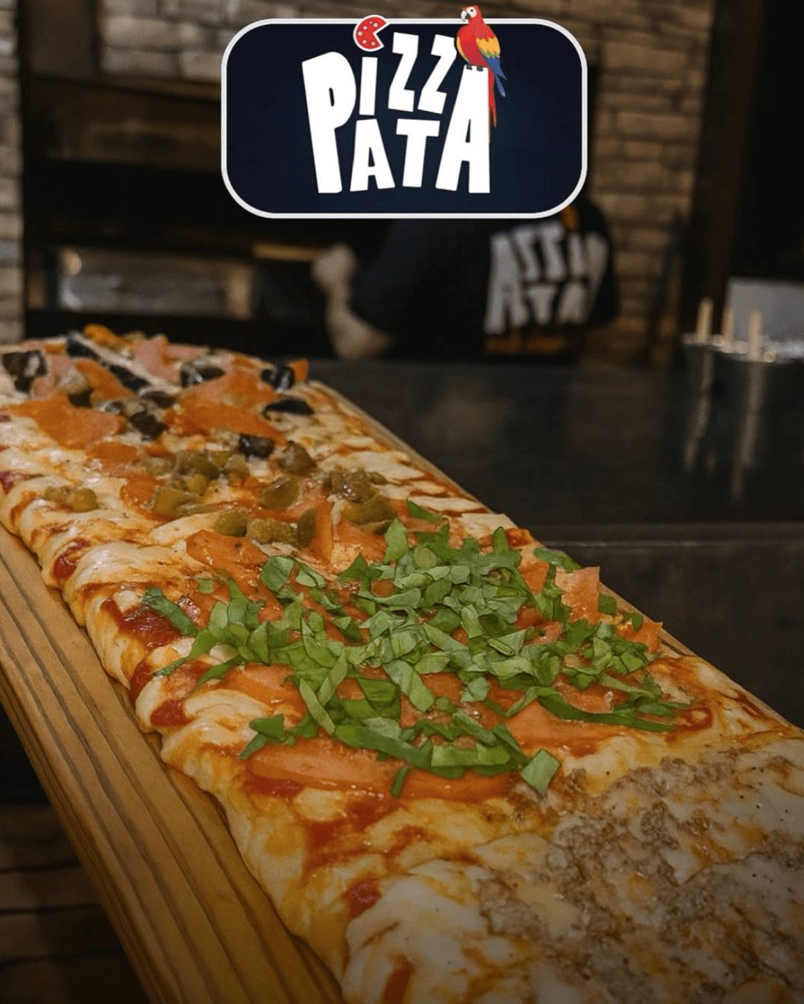 Pizza Pata's signature pizza sold by the meter on a wooden board in Jacó