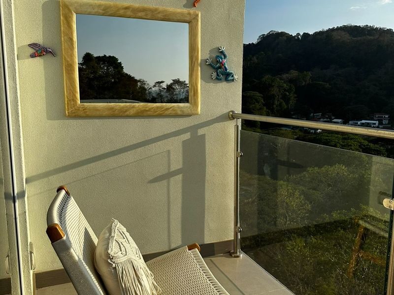 Private balcony with hammock lounger and glass railing overlooking lush green mountains near Punta Leona — buying property near Jaco Beach, Costa Rica