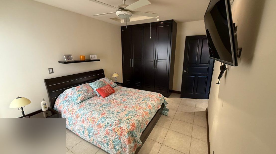 Master bedroom with colorful bedding, ceiling fan, and built-in wardrobe in the furnished villa at Sitio de Ensueno, Punta Leona