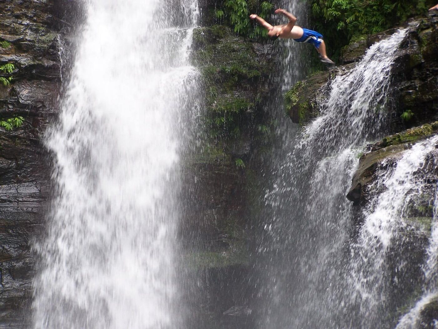 Rappelling down a tall rainforest waterfall