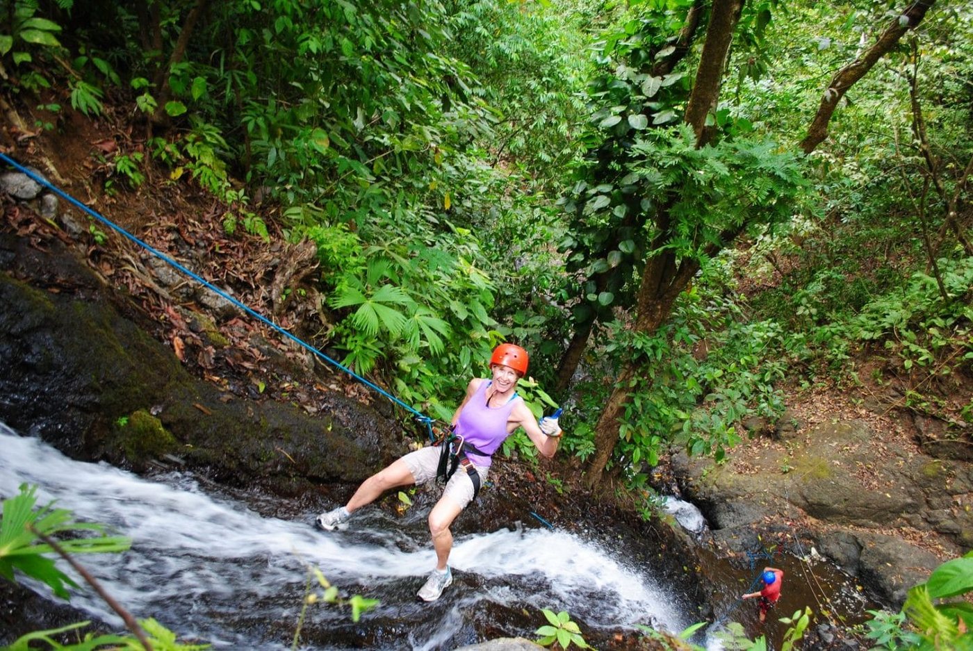 Guest rappelling down a mossy waterfall face