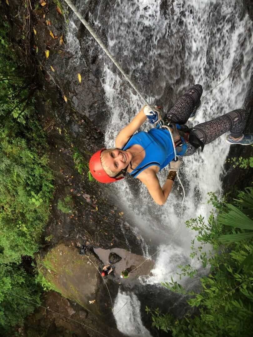 Adventurer descending a waterfall rope drop