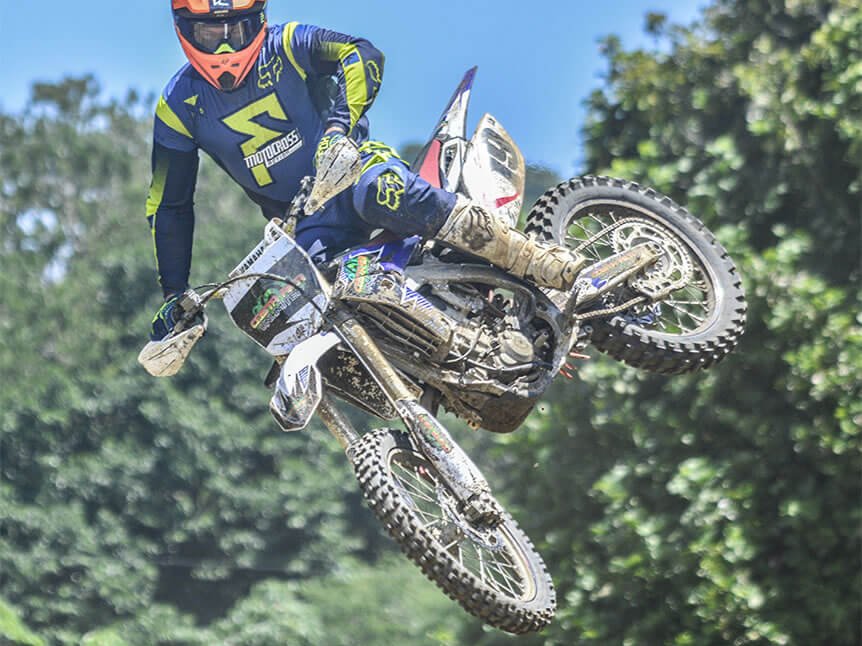 Enduro rider catching air over a jungle trail